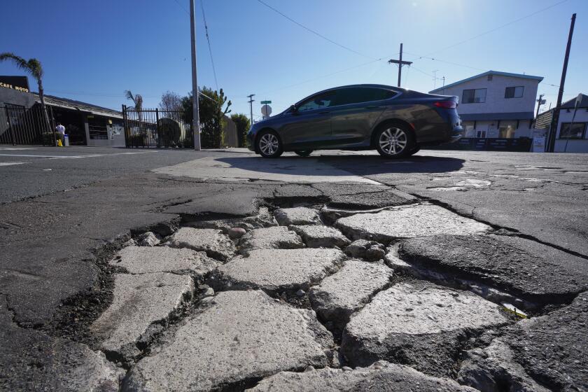 San Diego, CA - January 16: On Tuesday, Jan. 16, 2024, in San Diego, CA, motorists make their way past crumbling asphalt and concrete on the corner of National Avenue and S 26th Street in Barrio Logan. (Nelvin C. Cepeda / The San Diego Union-Tribune)