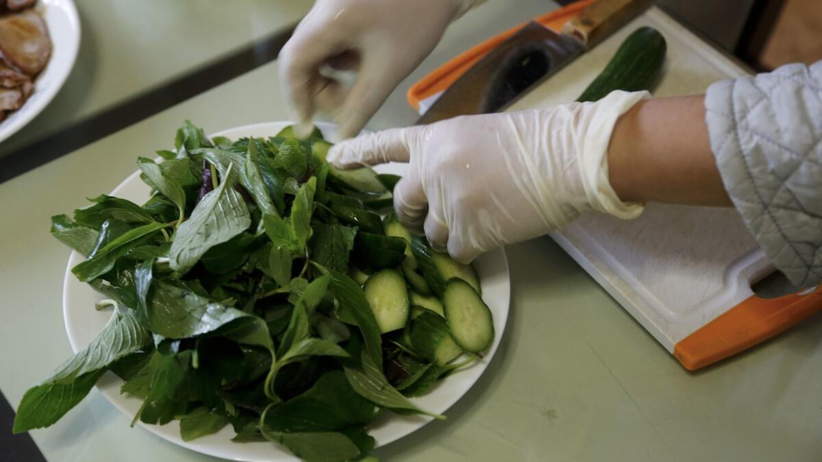As part of this afternoon's lunch, Hue Phan offers a salad bursting with fresh lettuce, cucumber and mint. (Mark Boster / Los Angeles Times)