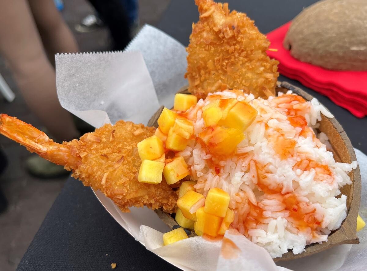 A coconut shrimp dish with rice and mango.