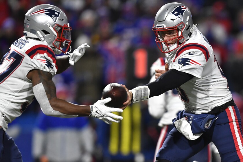 El quarterback de los Patriots de Nueva Inglaterra, Mac Jones, le entrega el balón al running back Damien Harris en la primera mitad del juego ante los Bills de Buffalo, el lunes 6 de diciembre de 2021, en Orchard Park, Nueva York. (AP Foto/Adrian Kraus)