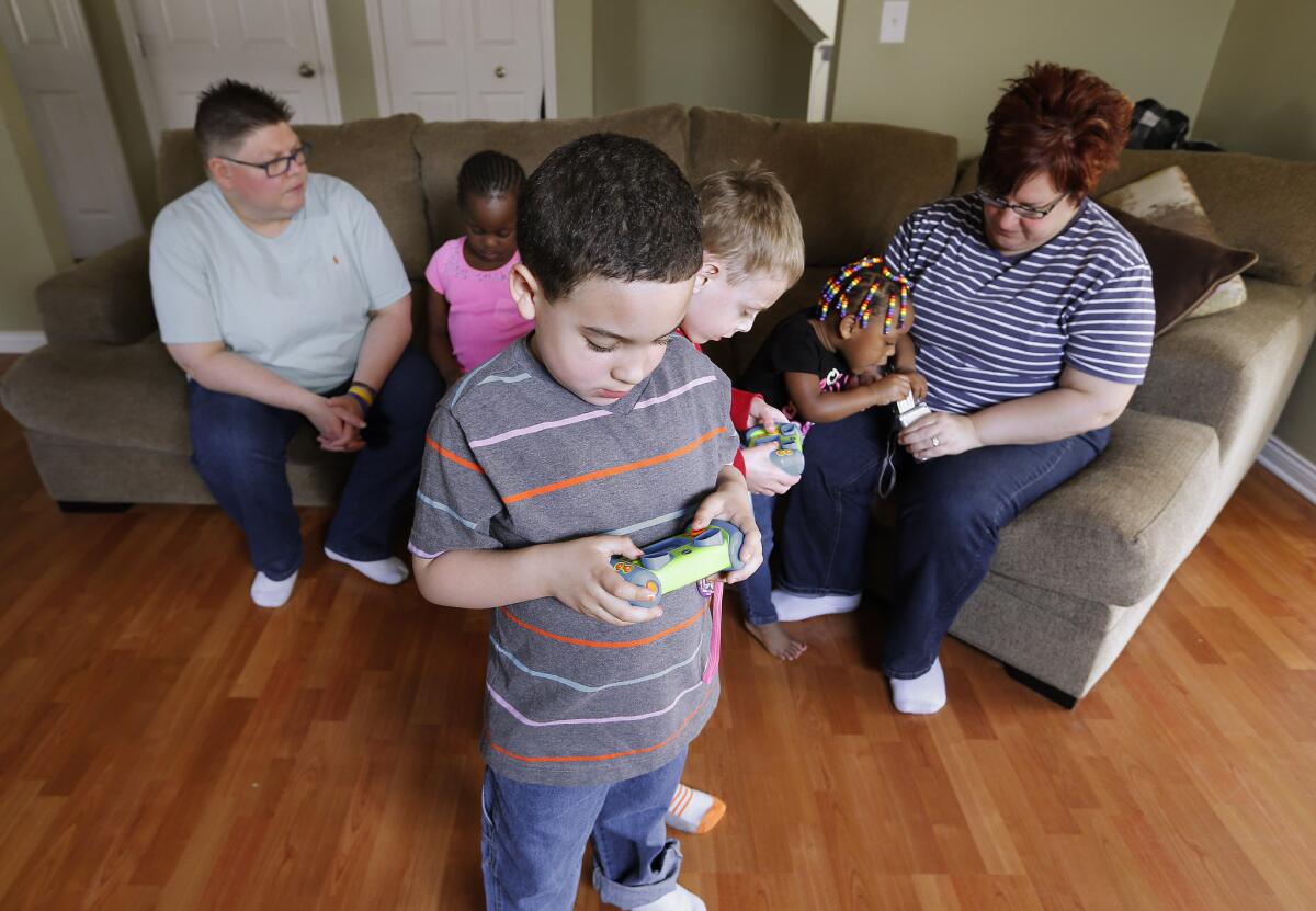 Jayne Rowse, left, and April DeBoer, right, sit with their adopted children Ryanne, 6, from left, Nolan, 6, Jacob, 5, and Rylee, 2, at their home in Hazel Park, Mich. on April 12, 2015.