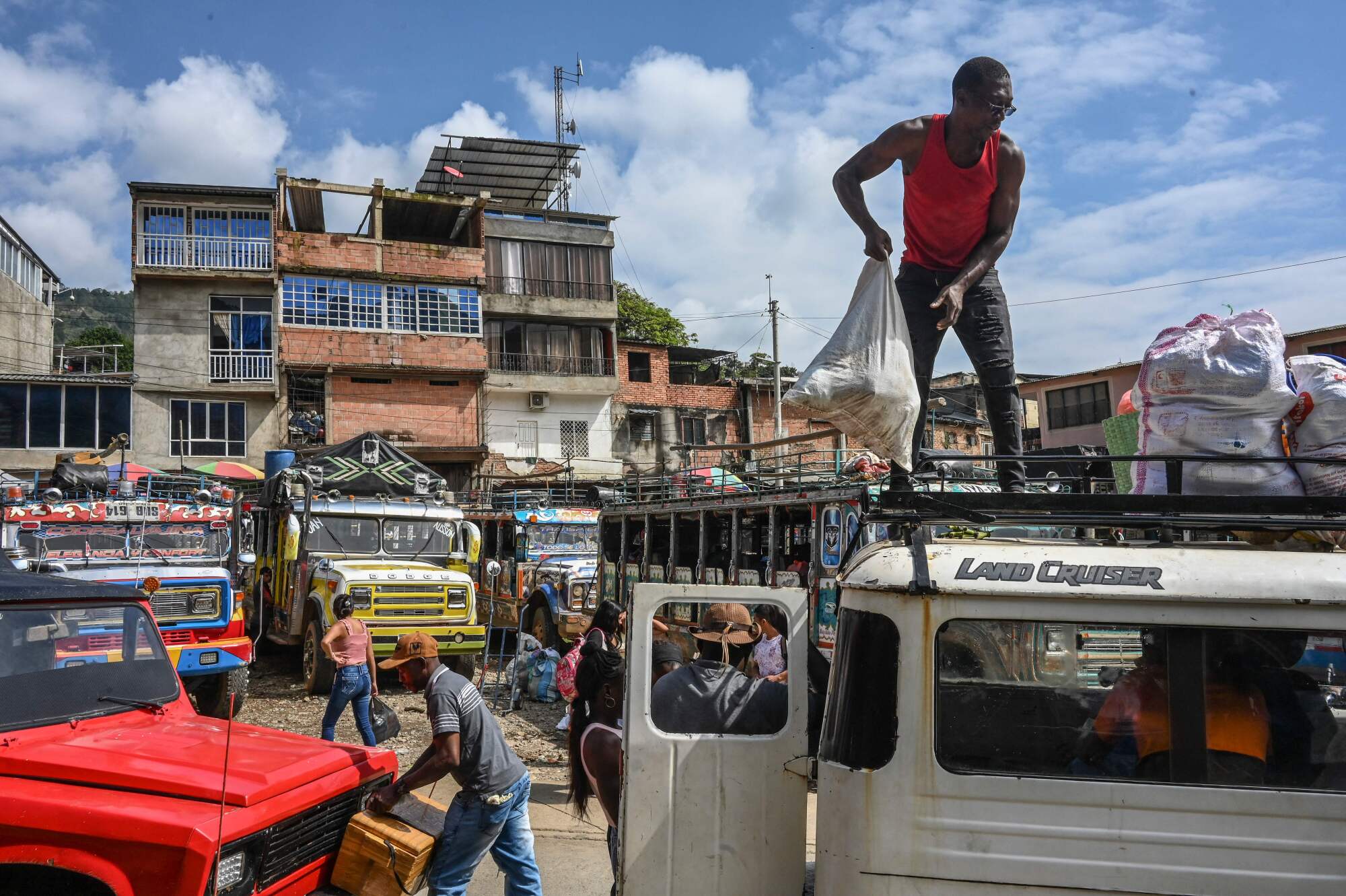 A man stands atop a truck, holding a bag