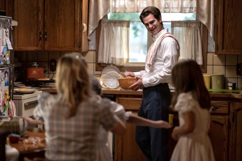A man stands by his daughters while washing dishes in a kitchen sink in an early 1980s kitchen