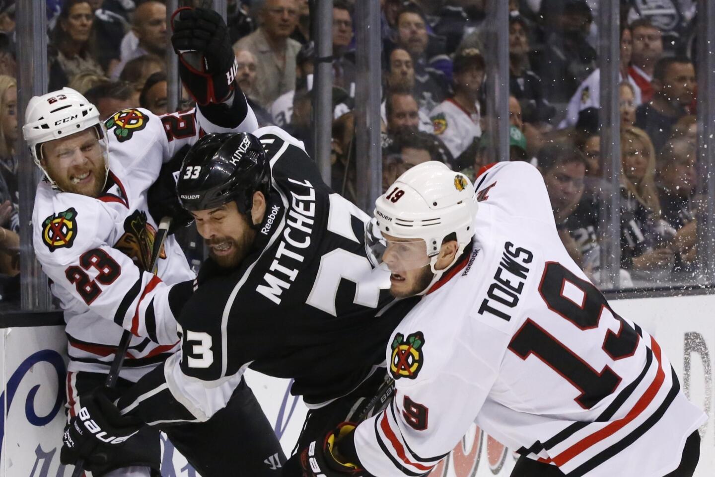 Kings defenseman Willie Mitchell, center, battles Chicago Blackhawks teammates Kris Versteeg, left, and Jonathan Toews along the boards during the second period of Game 4 of the Western Conference finals at Staples Center.