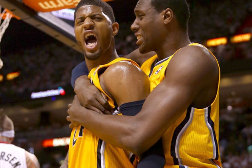 Pacers guard Paul George lets out a yell as he's embraced by teammate Ian Mahinmi after dunking against the Heat in the second half of Game 2 on Friday night in Miami.