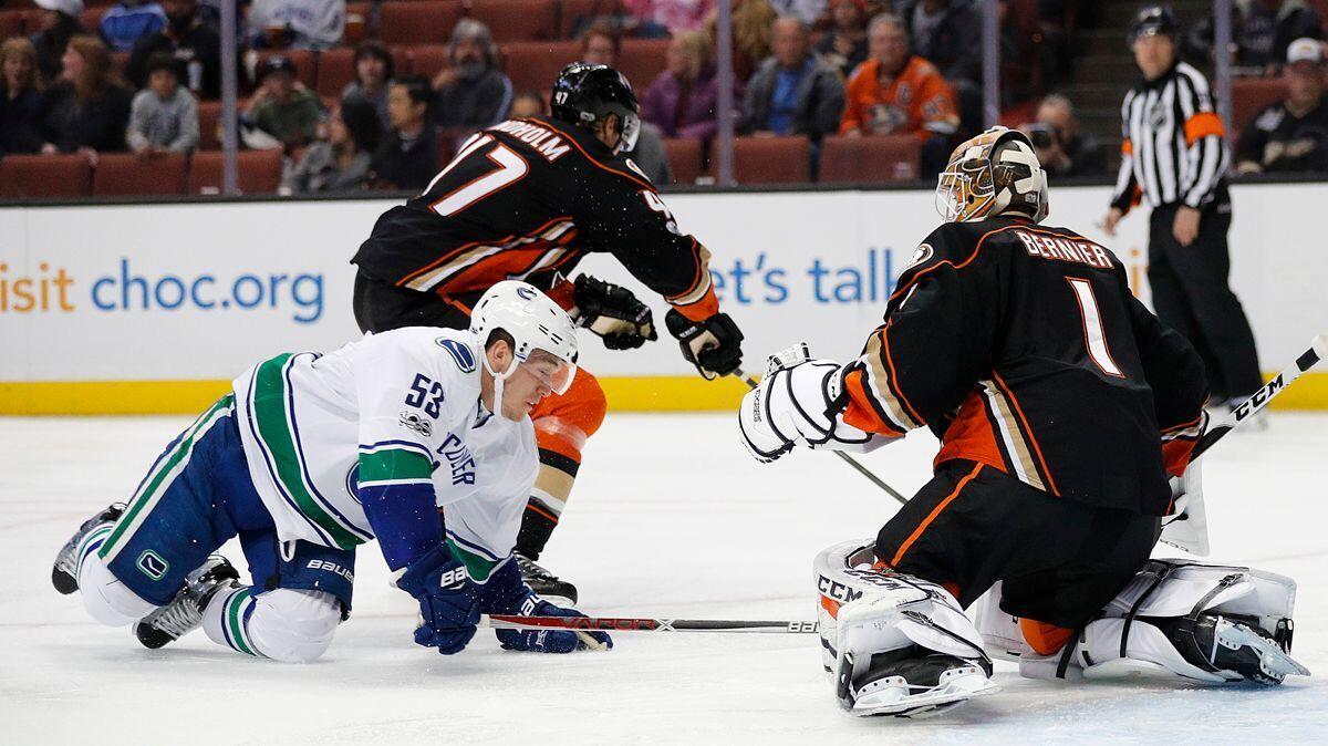 The Ducks' Hampus Lindholm, top left, takes the puck away from Vancouver's Bo Horvat in front of Ducks goalie Jonathan Bernier during their March game at Honda Center.