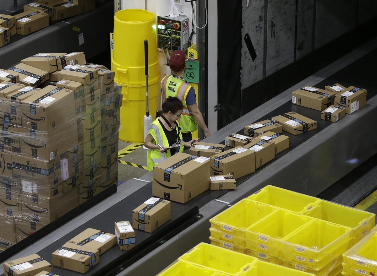 Two workers in yellow vests standing between conveyor belts carrying cardboard boxes