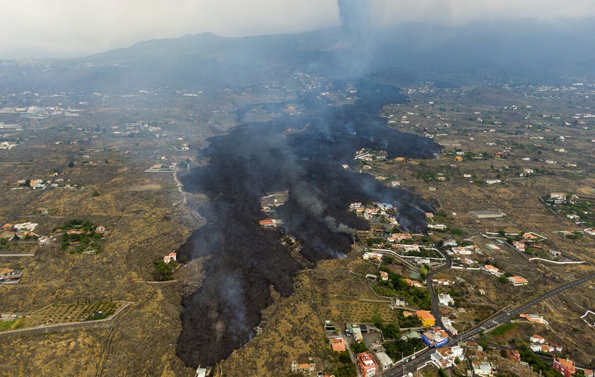 An aerial view shows lava from a volcano eruption flows destroying houses on the island of La Palma in Spain
