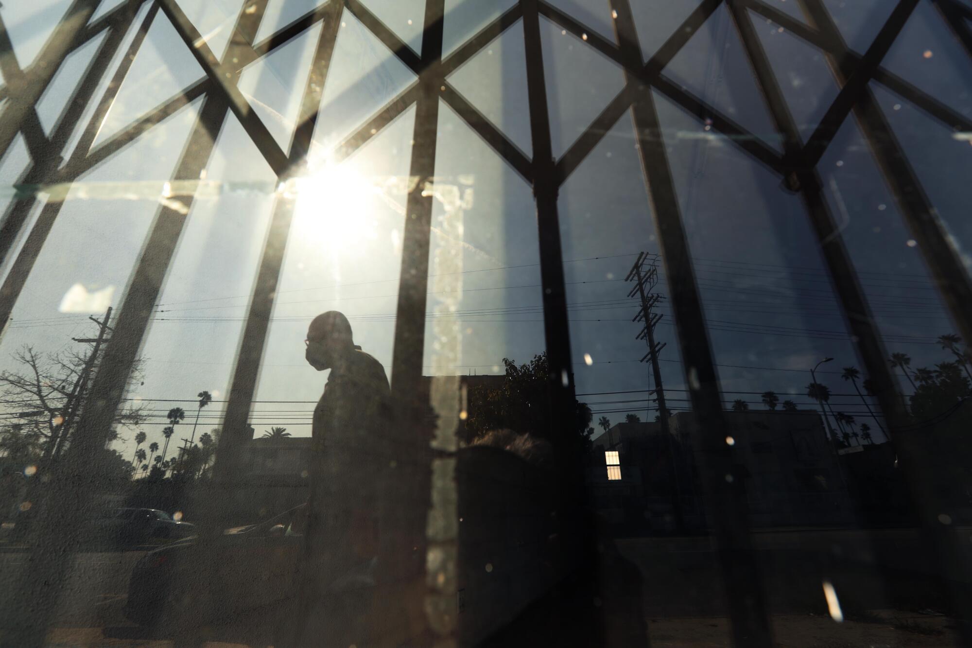 A pedestrian reflected in a window.