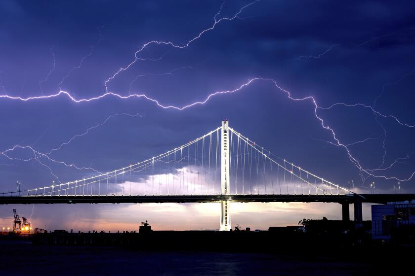 Lightning forks over the San Francisco-Oakland Bay Bridge as a storm passes over Oakland, Calif., Sunday, Aug. 16, 2020. Numerous lightning strikes early Sunday sparked brush fires throughout the region. (AP Photo/Noah Berger)