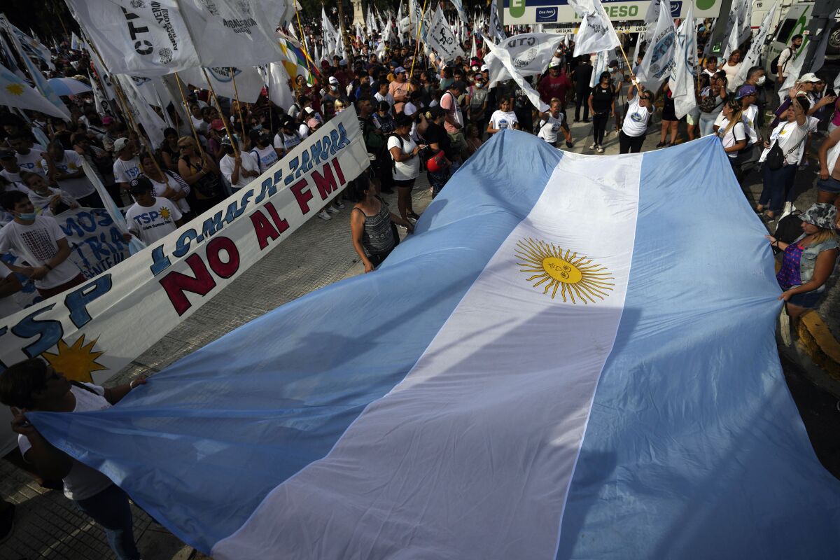 People display an Argentine national flag during a protest outside Congress as senators prepare to vote on a law to ratify the government’s agreement with the IMF to refinance some $45 billion in debt, in Buenos Aires, Argentina, Thursday, March 17, 2022. (AP Photo/Natacha Pisarenko)