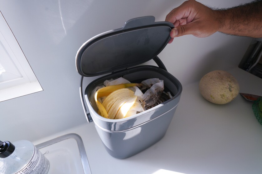Victor Sanchez, at his home in National City, places food waste in a special countertop food container. 