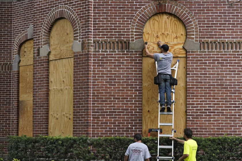 Workers from Specialized Performance Delivered 24:7 board up the windows on the historical Henry B. Plant Hall on the campus of the University of Tampa ahead of Hurricane Ian Tuesday, Sept. 27, 2022, in Tampa, Fla. Ian is predicted to make landfall somewhere on Florida's west coast. (AP Photo/Chris O'Meara)