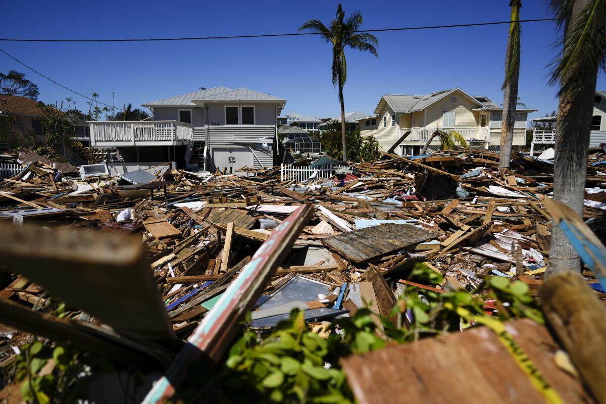 A road is filled with a tall pile of debris from destroyed homes and businesses