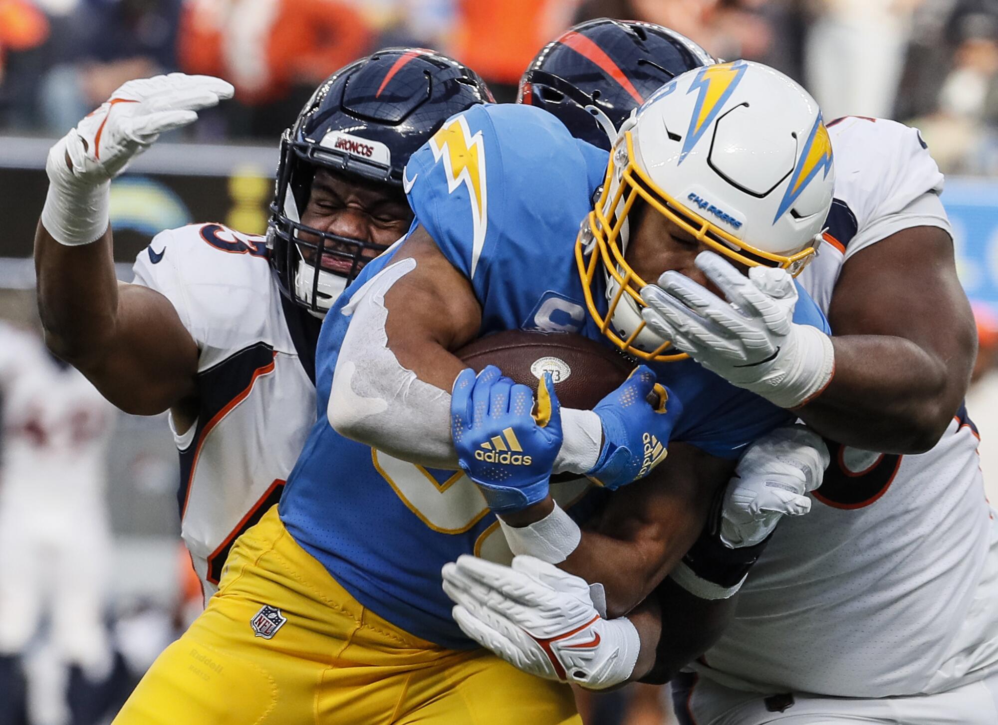 Broncos inside linebacker Micah Kiser and defensive end Shelby Harris tackle Chargers running back Austin Ekeler.