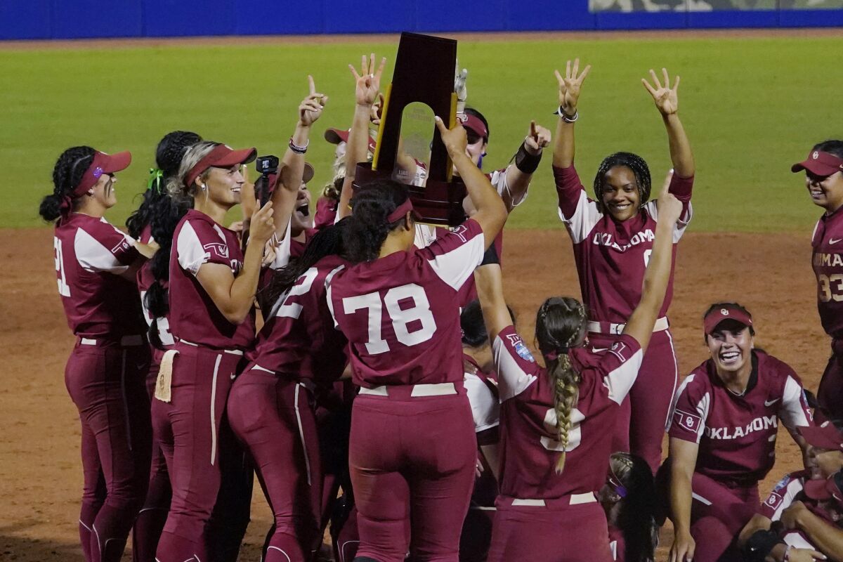Oklahoma players celebrate with the trophy after defeating Texas in the NCAA Women's College World Series softball finals Thursday, June 9, 2022, in Oklahoma City. (AP Photo/Sue Ogrocki)