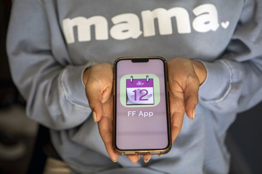 A woman holds open a cell phone with a fertility app