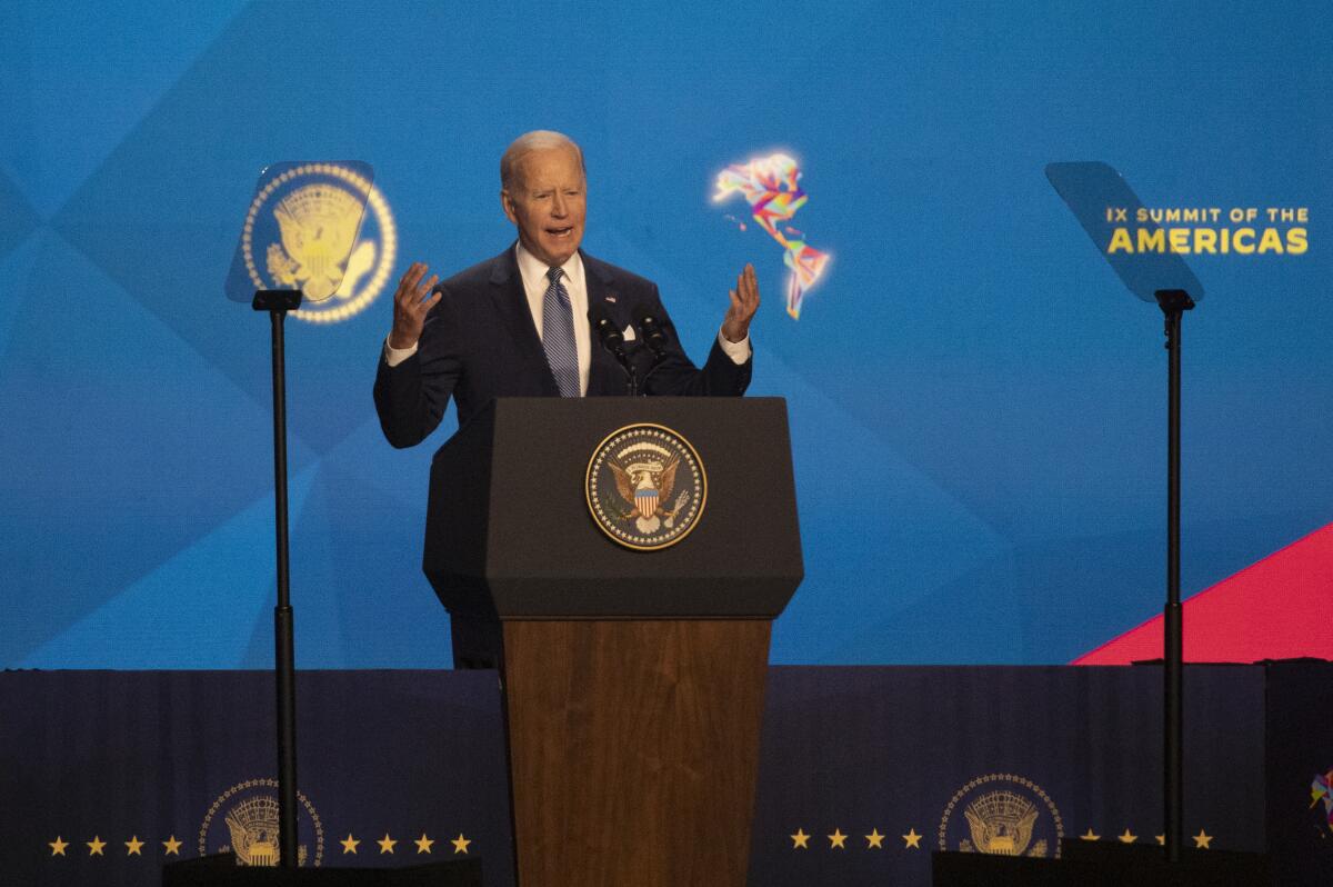 President Biden speaking onstage in front of a Summit of the Americas logo