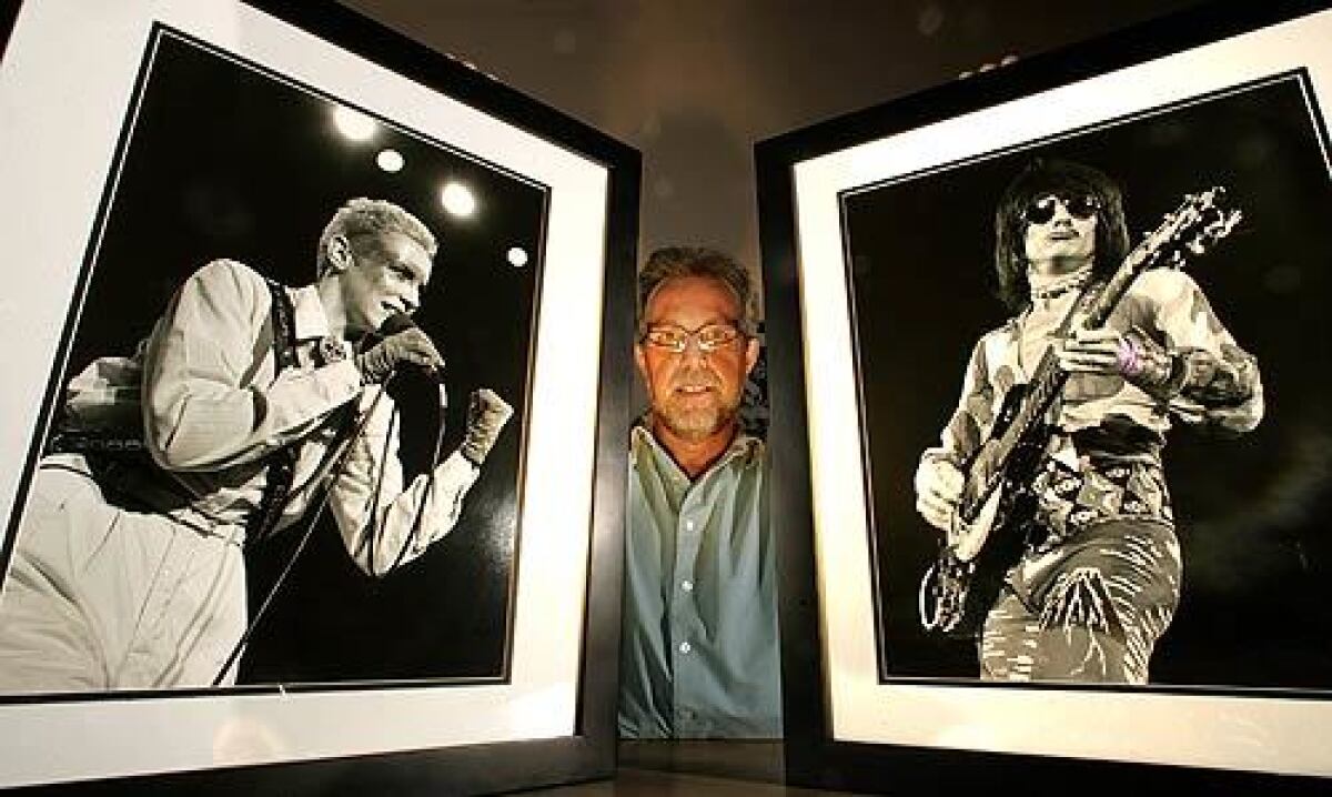 Greg Papazian holds photographs he took of two of his favorite rock musicians: Annie Lennox, taken in 1983 at the Palace Theatre in Hollywood, and Ron Wood, taken at the Anaheim Convention Center in 1973.