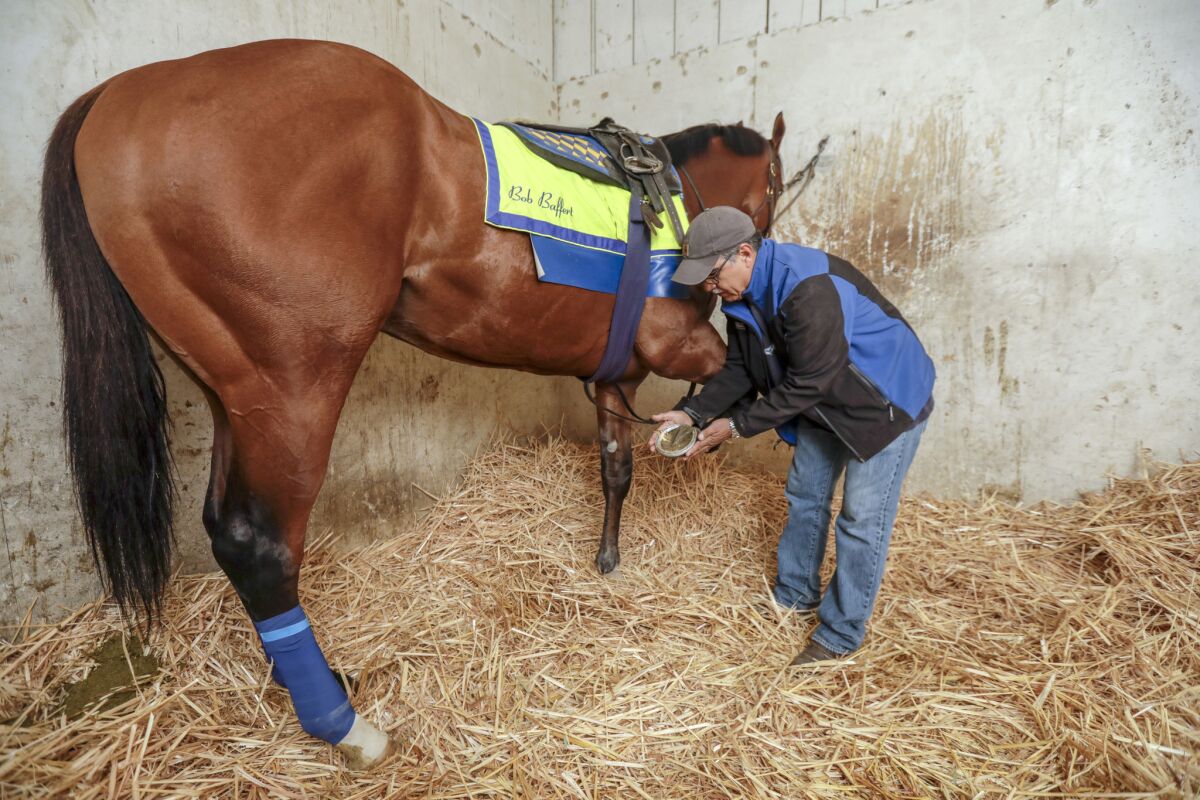 Pascual Rivera inspects the shoes of a horse in Bob Baffert's barn at Santa Anita Park.