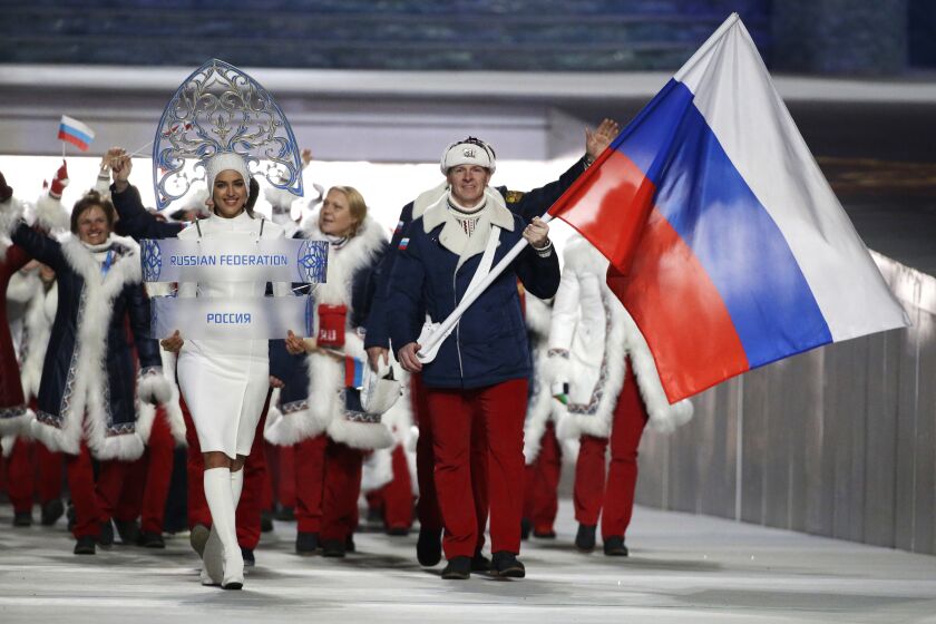 FILE - In this Feb. 7, 2014 file photo Alexander Zubkov of Russia carries the national flag as he leads the team during the opening ceremony of the 2014 Winter Olympics in Sochi, Russia. at left is model Irina Shayk carrying the Russian placard. (AP Photo/Mark Humphrey, file)