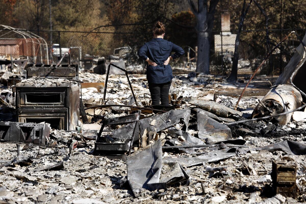 Emily Learn surveys the wreckage of her parents' home that was destroyed in the Redwood Valley fire.