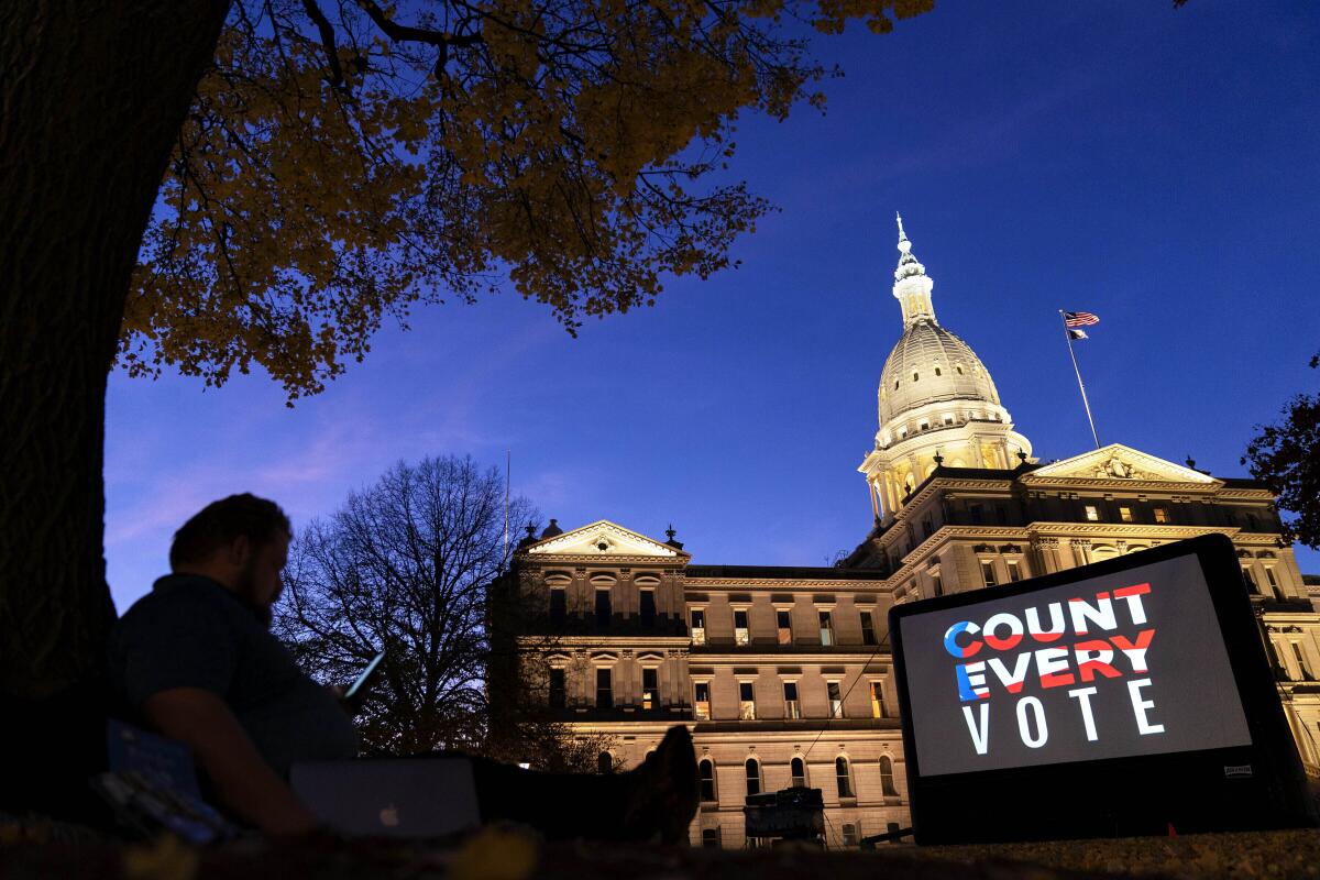 La frase "Cuenta cada voto" se muestra en una pantalla frente al Capitolio estatal de Lansing