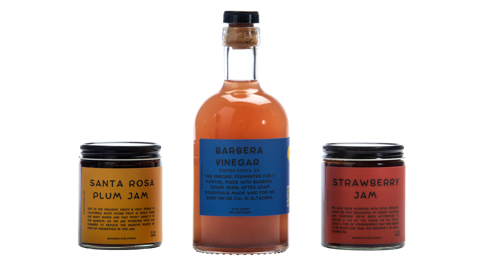 Two jars of plum and strawberry jam flank a bottle of vinegar by Sunset Cultures