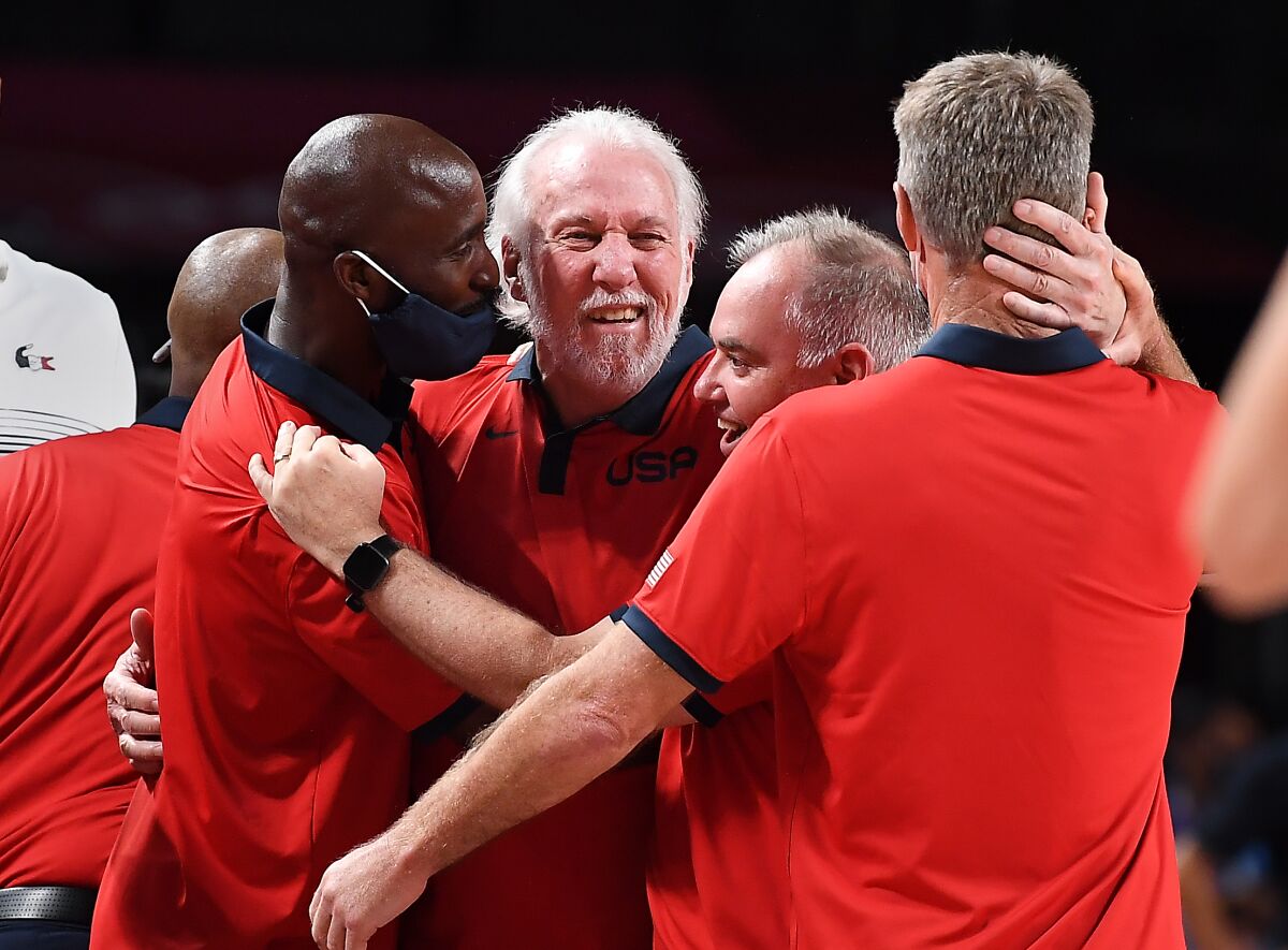 Basketball coach Gregg Popovich hugs staff members at the Tokyo Olympics.