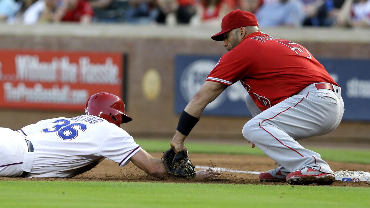 Angels first baseman Albert Pujols tags out the Rangers' Jared Hoying on a pickoff throw by Nick Tropeano during a game May 23.