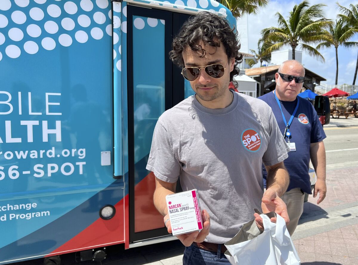 A man hands out samples of Narcan, which can reduce opioid overdoses, to spring breakers on Fort Lauderdale Beach, Fla.