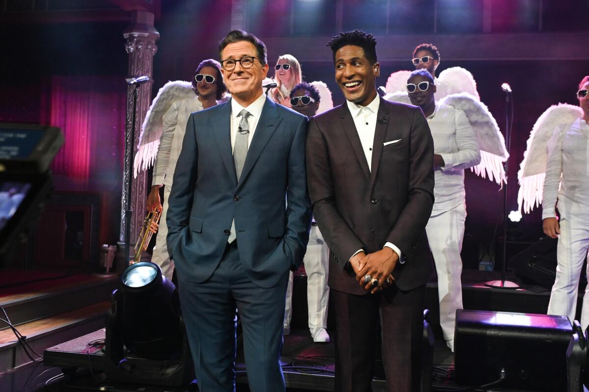 Two men in suits standing in front of a choir dressed in angel costumes