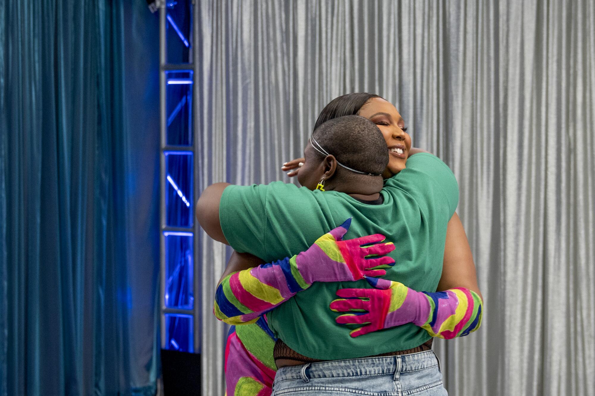 Two women wearing colorful clothing hug