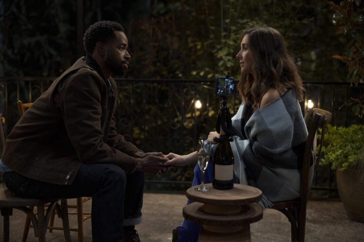 A man and woman hold hands while looking into each other's eyes.