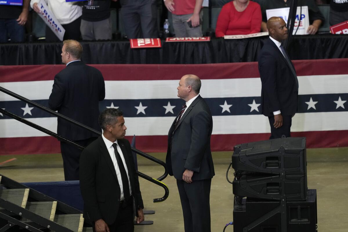 Secret Service officers stand near a stage looking around.