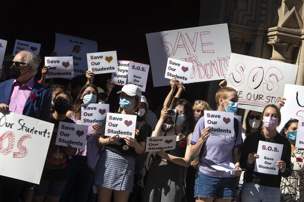 USC students protest and hold signs reading 'save our students.'
