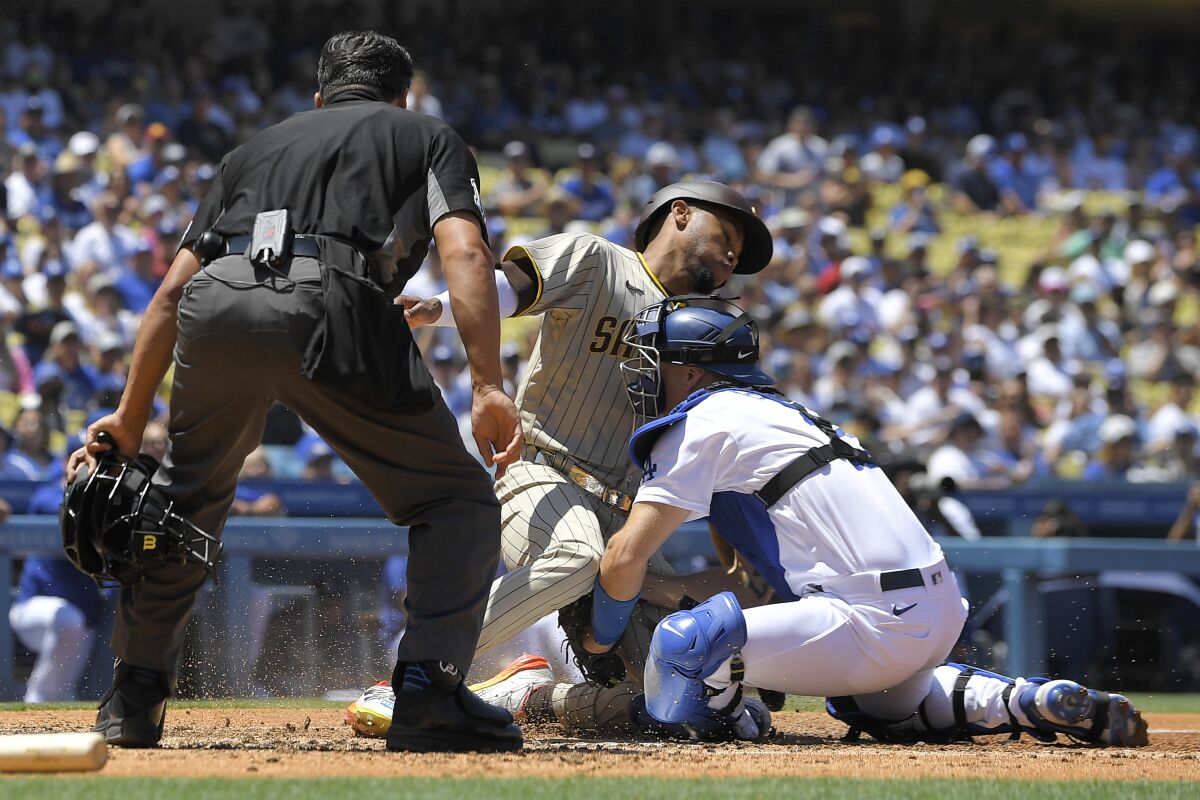 San Diego Padres' Jose Azocar, center, is tagged out by Los Angeles Dodgers catcher Austin Barnes, right, as he tries to score on a fielder's choice hit by Manny Machado as home plate umpire Charlie Ramos watches during the third inning of a baseball game Sunday, July 3, 2022, in Los Angeles. (AP Photo/Mark J. Terrill)
