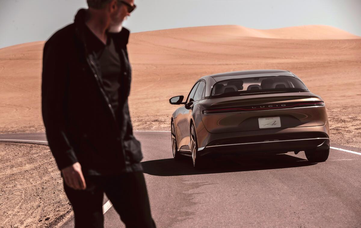 A man in the desert looks at a Lucid Air electric car in a 2020 promotional photograph. 