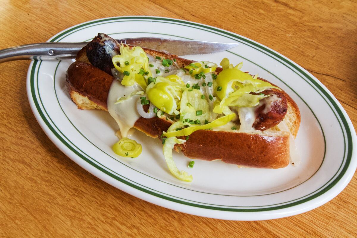 A sausage hot dog smothered in cheese and pepperoncini at restaurant Coucou.