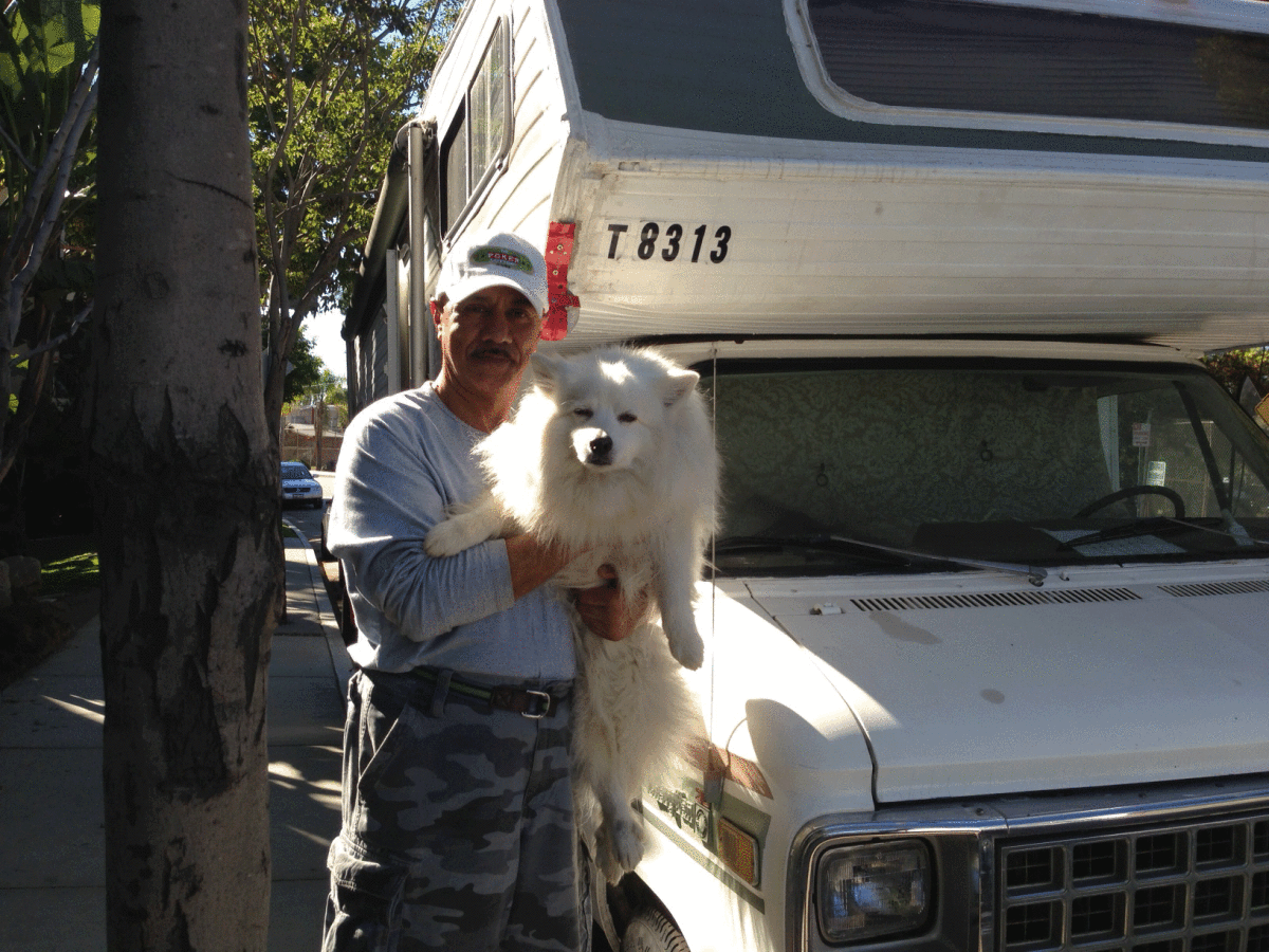 Farhad Alexander-Alizadeh stands with his dog Perry in front of his RV parked in Brentwood.