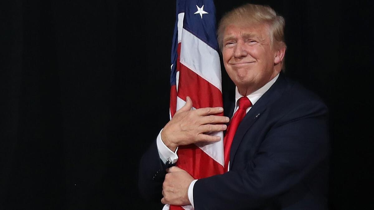 President-elect Donald Trump hugs the American flag at a campaign rally Oct. 24 in Tampa, Fla.