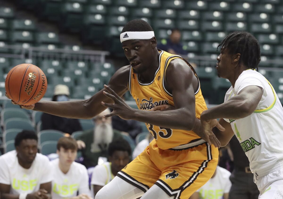 FILE - South Florida forward Jalyn McCreary, right, guards Wyoming forward Graham Ike (33) during the first half of an NCAA college basketball game Dec. 25, 2021, in Honolulu. The No. 22 Cowboys have their first AP Top 25 ranking since 2015 and play two games this week. (AP Photo/Marco Garcia, File)