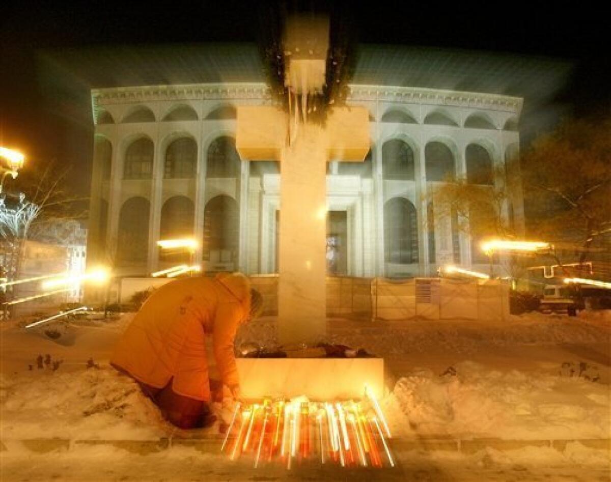 A woman lights candles next to a cross during a memorial event for the anti-communist uprising 20 years ago, in the University Square in Bucharest Romania, Monday, Dec. 21, 2009. This week Romanians commemorate 20 years since communist dictator Nicolae Ceausescu fled Bucharest during a popular uprising on Dec. 22, 1989, after ruling Romania for 25 years. Ceausescu was executed together with his wife Elena on Dec. 25, 1989. More than a thousand people are reported to have lost their lives during the Romanian revolution. (AP Photo/Vadim Ghirda)