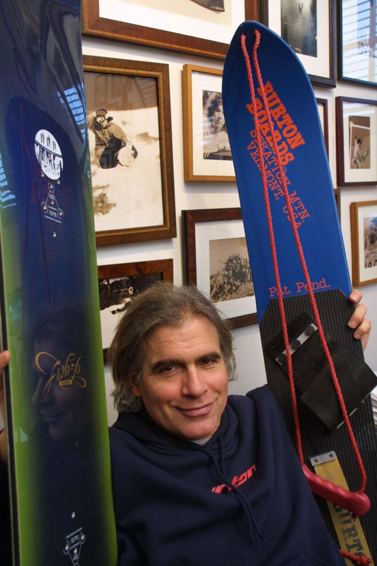 Jake Burton Carpenter, owner of Burton Snowboards, shows an early model, right, and the latest version of his snowboards, left, at his office in Burlington, Vt., in 2002.