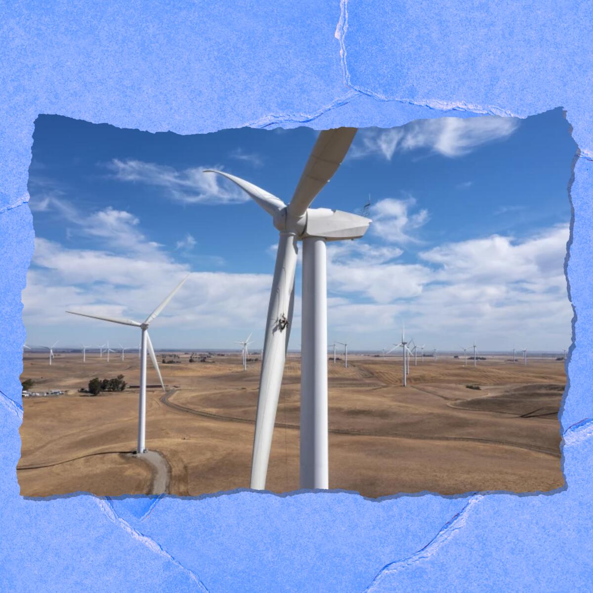 Closeup of the blades of a massive wind turbine, with other turbines in the distance.