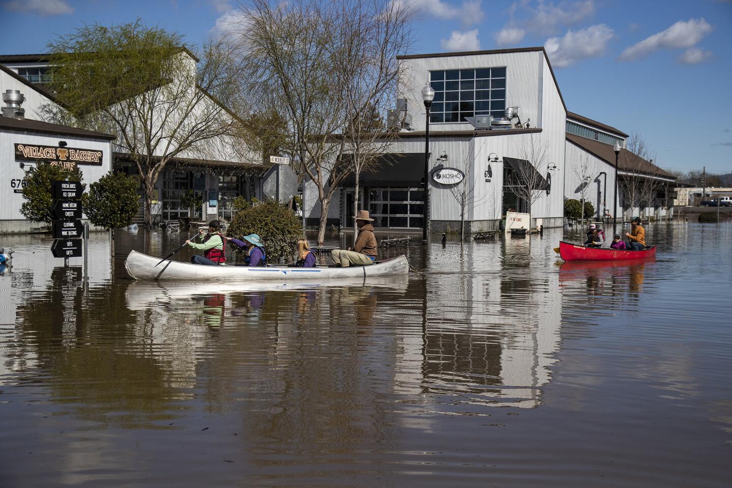 Algunas personas se transportan en canoas en las inundaciones que rodean el mercado de Barlow en Sebastopol, California.