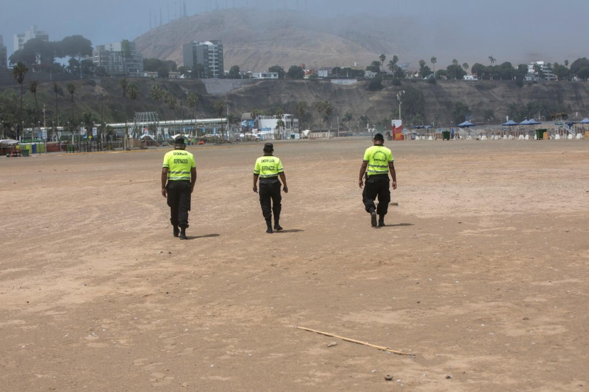 Police walk along the Lima beach to warn off would-be swimmers on March 24.