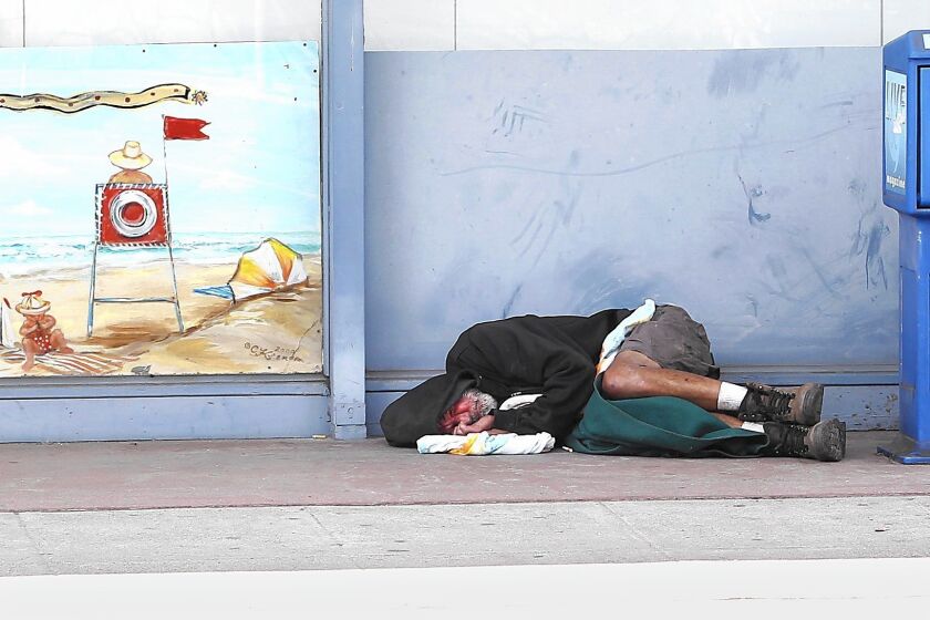 A homeless man sleeps on the curb at Mountain and south coast highway in Laguna. The Alternative Sleeping Location offers 45 beds at night.