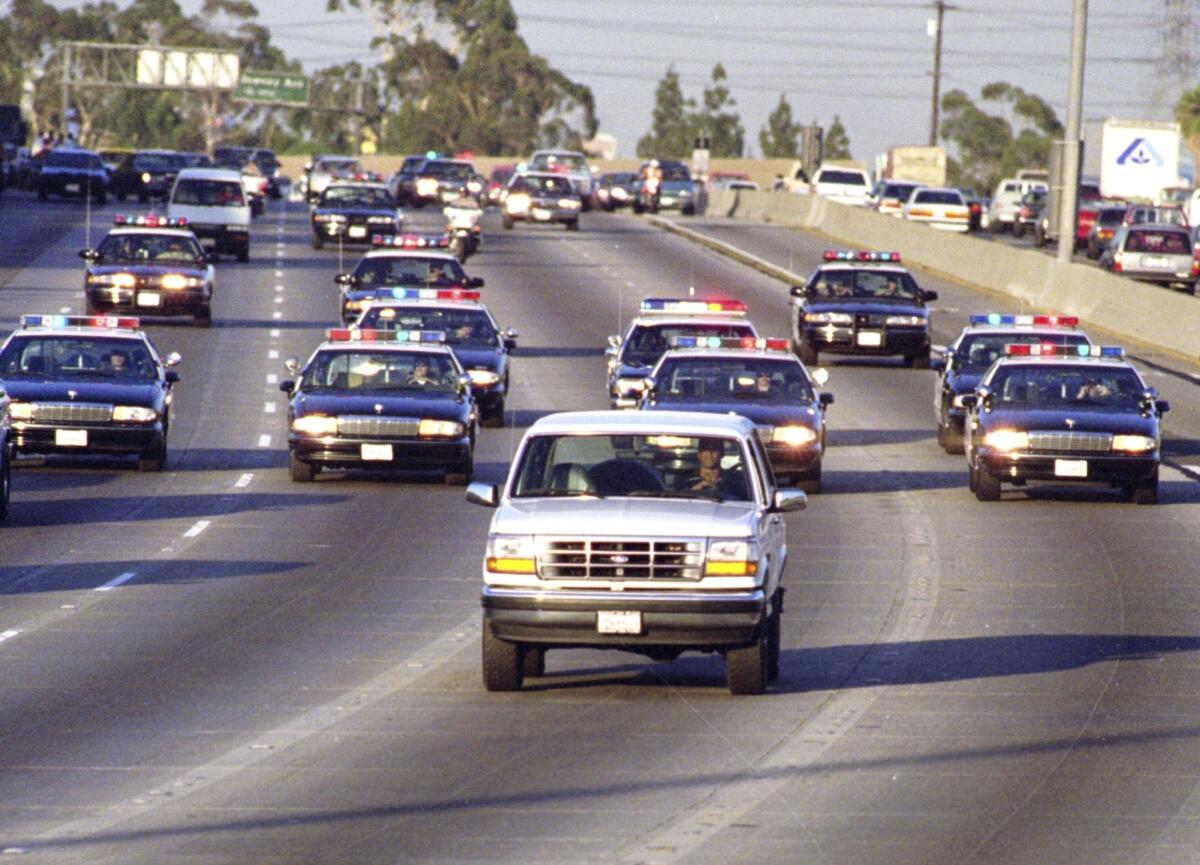 California Highway Patrol units chase Al Cowlings, who is driving the white Bronco, and O.J. Simpson, hiding in the rear, on the 91 Freeway shortly after Simpson was charged in slayings.