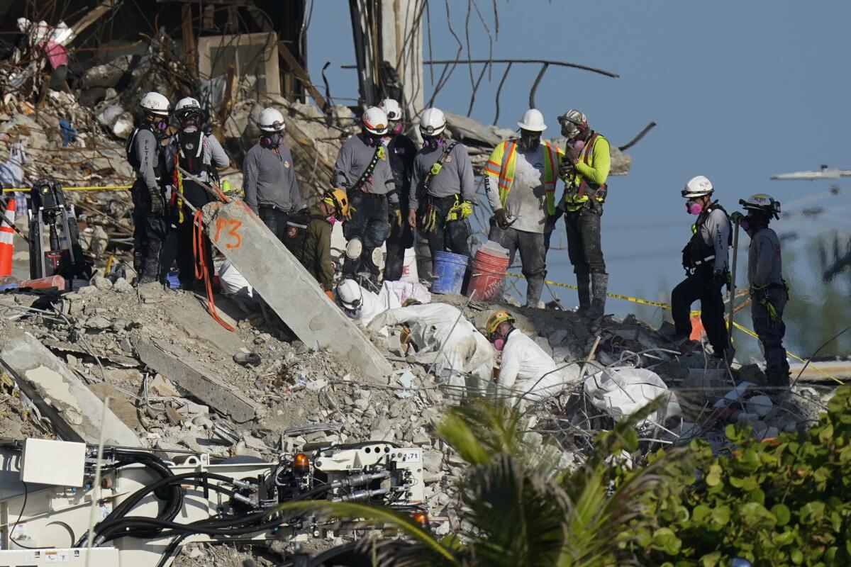 People in hard hats work amid rubble.